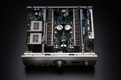 Innenansicht eines silbernen Denon PMA-1600NE Stereo-Hi-Fi-Verstärkers mit geöffneter Abdeckung, die die elektronischen Komponenten zeigt