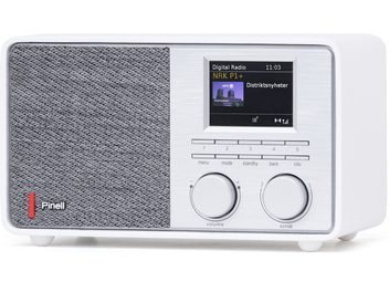 Tischradio Pinell Supersound 201W weiß aus Kunststoff mit Front, die zwischen grauem Stoff-Lautsprechergitter und gebürstetem Aluminium-Panel mit Farbdisplay, Tastenreihen und zwei großen Drehreglern aufgeteilt ist, Ansicht von vorne rechts im Dreiviertelprofil