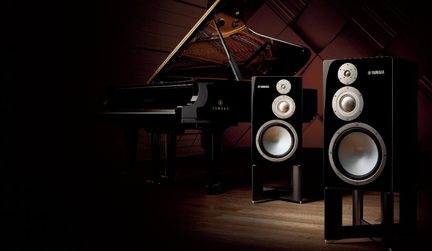 Auki oleva kiiltävän musta flyygeli ja kaksi kiiltävän mustaa Yamaha-kaiutinta metallikartioilla jalustoilla