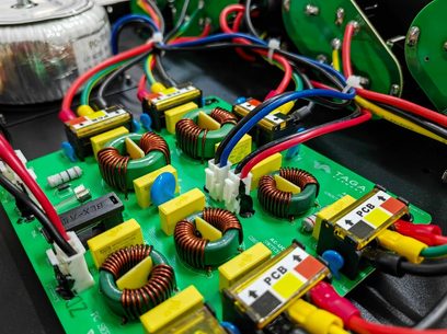 Grønne elektroniske kredsløb med gule og røde komponenter, flerfarvede kabler, på en åben sort kabinet