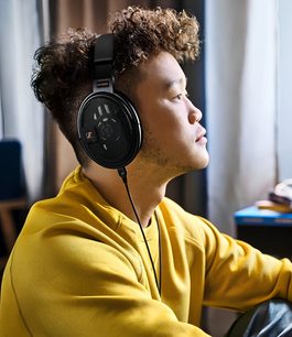 Casque audio Sennheiser HD 660S2 noir porté par un homme de profil, les yeux fermés, sur un fond flou intérieur