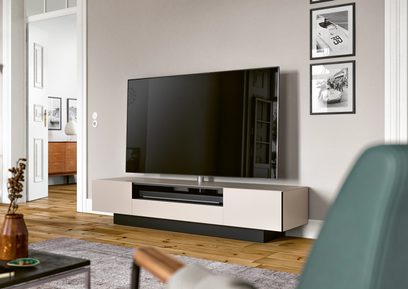 Lavt hvidt og gråt TV-møbel med skuffer, hylder og central plads til fladskærm i et moderne stue