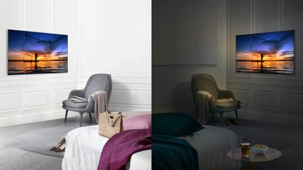 To TV-er som viser en solnedgang, to grå og beige lenestol, et grått teppe, et salongbord med en kopp