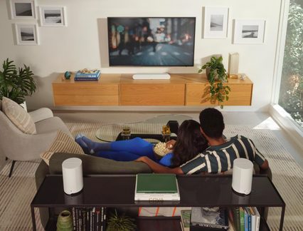 Mesh Wi-Fi-system med to hvide cylindriske routere på konsol bag sofa i stilfuld stue