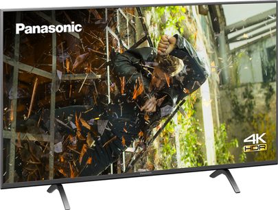 Panasonic TX-55HX900E 4K HDR-tv set forfra, skærmen viser en tæt skov med grønne og brune blade