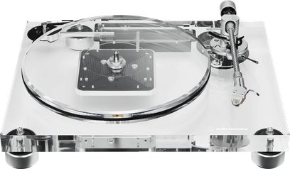 Audio Technica AT-LPA2 transparent akryl-pladespiller, set fra trekvart forfra, med gennemsigtigt rundt pladetallerken, sølvfarvet metal-tonearm til højre og fire sorte cylindriske fødder