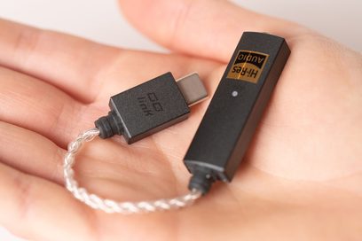 Bærbar iFi Audio GO Link lydkonverter i sort set forfra, tilsluttet et hvidt flettet kabel via USB-C