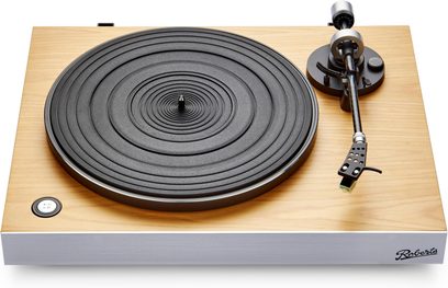 Giradischi hi-fi Roberts Stylus Luxe in legno chiaro con frontale in alluminio argentato, piatto nero striato e braccio di lettura in metallo nero e argento, pulsante di velocità rotondo 33/45 giri, logo visibile sul frontale, vista dall'alto leggermente inclinata