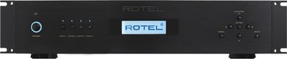 Rotel RMB-1555 sort multikanal-effektforstærker, frontpanel med knapper, stik og blå LCD-skærm der viser "ROTEL"