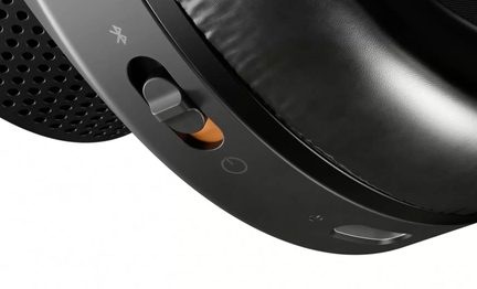 Tæt påbillede af en sort plastikheadset, set nedenfra, skyder, strømikon og Bluetooth-ikon, perforeret gitter