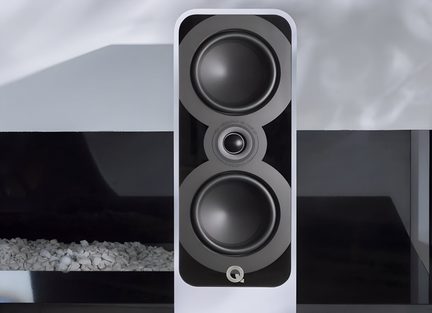 White column speaker in a lacquered cabinet with a glossy black front, two black circular drivers and a central tweeter aligned vertically, close-up front view