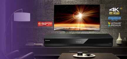 Leitor Blu-ray preto em metal com acabamento fosco, vista frontal, caixa retangular plana com fachada de vidro e display digital central
