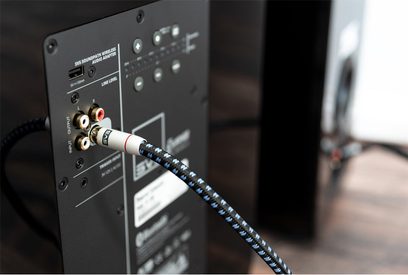 Cabo para subwoofer SoundPath Subwoofer 1m conectado na parte traseira de um aparelho de áudio preto com conectores RCA