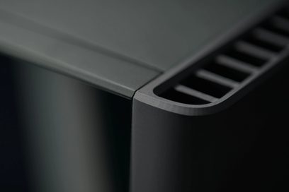 Amplificator de putere high-fidelity Michi M8 negru, vedere de aproape a unui colț superior cu suprafață netedă și grilaj.