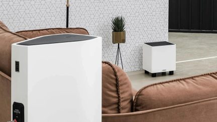 Bílý subwoofer Sonetto s černou horní částí, prezentovaný v moderním obývacím pokoji ze dvou úhlů