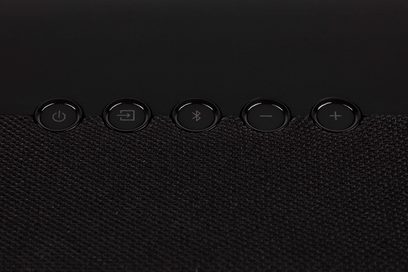 Denon DHT-S216 sort soundbar, set oppefra, 5 runde indfældede knapper med symboler, overflade med voksmønster