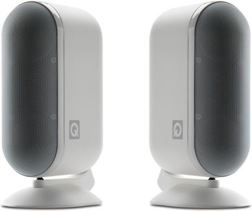 Dvi baltos kompaktiškos Q Acoustics 7000LRi kolonėlės, priekinis vaizdas, juodi groteliai, apvalios kojelės