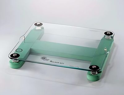 Rechteckige transparente Glasplatte mit 4 grünen zylindrischen Füßen an den Ecken auf weißem Hintergrund