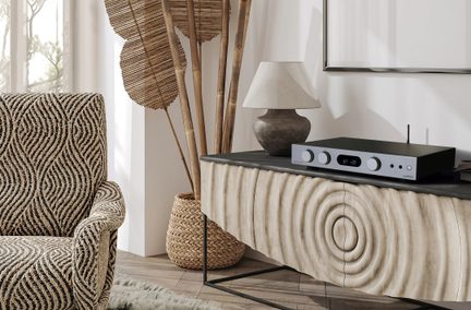 Amplificatore stereo Audiolab nero e argento su madia in legno dal design ondulato in soggiorno dallo stile naturale