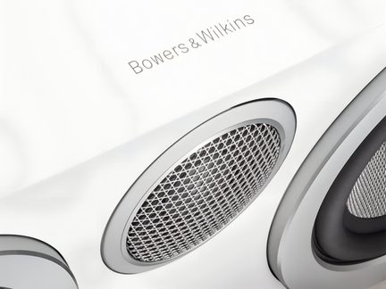 Біла акустична колонка Bowers & Wilkins крупним планом з овальною металевою решіткою та боковим твіттером
