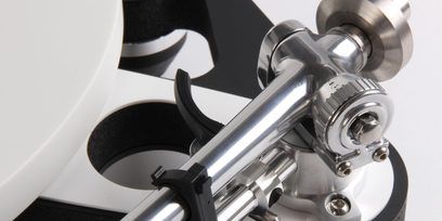 Arm för skivspelare Rega RB3000, närbild, silverfinish, svart stöd, vit tallrik i bakgrunden