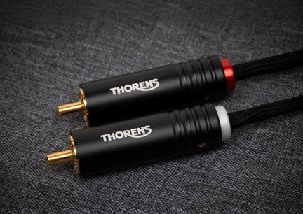 Par med RCA-hannkontakter, sylindriske hus i svart anodisert aluminium med hvit « THORENS »-påskrift, gullbelagte pinner, røde og hvite identifikasjonsringer, sort flettet kabel, sett ovenfra i lett skrå vinkel