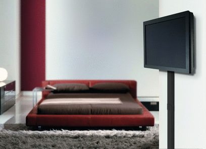 Rød sofa på gråt tæppe, fladskærms-tv på sort møbel, sort Vogel's CABLE 4 kabelbakke monteret på hvid væg