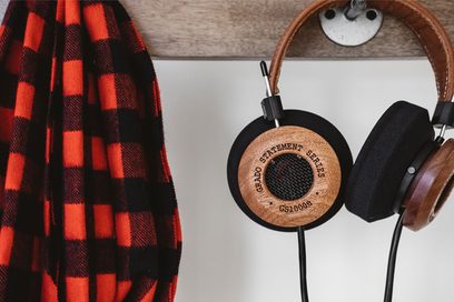 Åbent hi-fi hovedsæt Grado GS1000e i lyst træ, set fra siden, placeret på en holder, ved siden af et ternet rødt og sort tørklæde