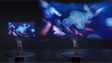 Two projectors on round tables cast luminous jellyfish onto a dark wall, creating colorful images.