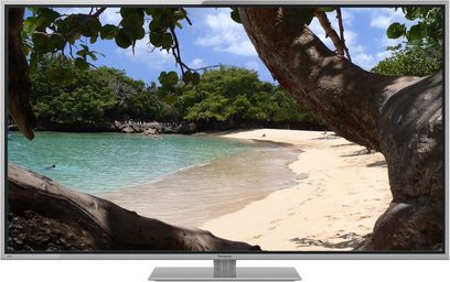 Panasonic TX-L60ET5E-fladskærm, der viser et tropisk strandmiljø med hvidt sand, turkisblåt vand, træer og klipper