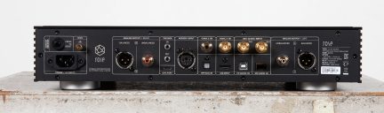 Juodo garso įrenginio galinis vaizdas su XLR, RCA, koaksialiniais, optiniais, USB jungtimis, maitinimo lizdu, metalinėmis kojelėmis