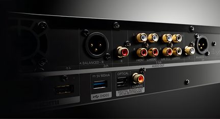 Artimo įrenginio, turinčio auksinius RCA, XLR, optinius, koaksialinius, USB ir HDMI įvadius, juodo metalo galinio plano nuotrauka