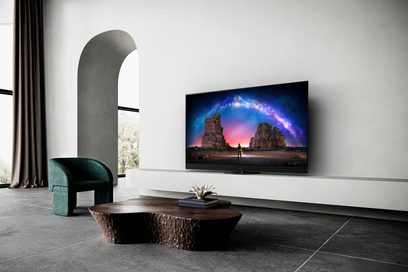 Panasonic TX-65LZ2000E-fladskærms-tv, der viser et galaktisk landskab, placeret på et træmøbel i et moderne interiør