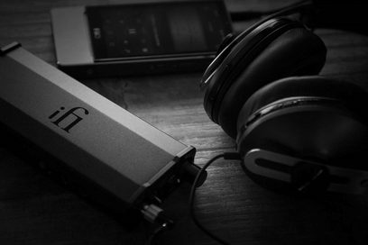 Convertisseur audio DAC iFi Audio Micro iDSD Black Label, casque audio, vue rapprochée de profil sur fond bois foncé