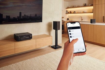 Mobilapp til styring af multiroom-lyd på smartphone, moderne stue med hjemmebiograf-forstærker og sort højttaler