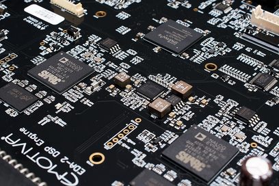 Sort printplade med mange rektangulære og firkantede elektroniske chips af forskellige størrelser loddet på