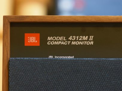 Enceinte bibliothèque JBL 4312M II, vue de face, grille noire, logo JBL orange, texte blanc sur fond noir