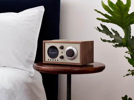 Træbordradio i brun, cremefarvet front, stort drejeknap og cirkulært display, set fra venstre trekvart